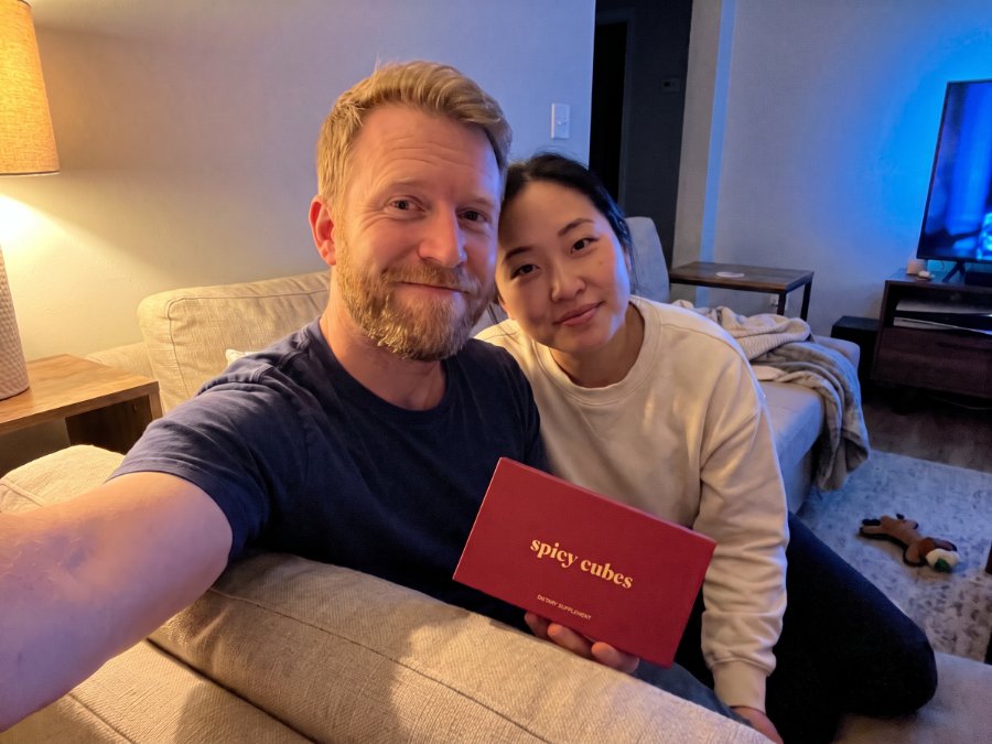 A couple on a sofa holding the red Spicy Cubes box